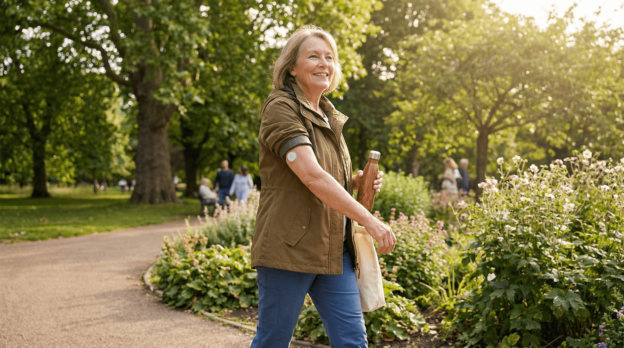 Older woman walking in a park with a continuous glucose monitor on her arm.